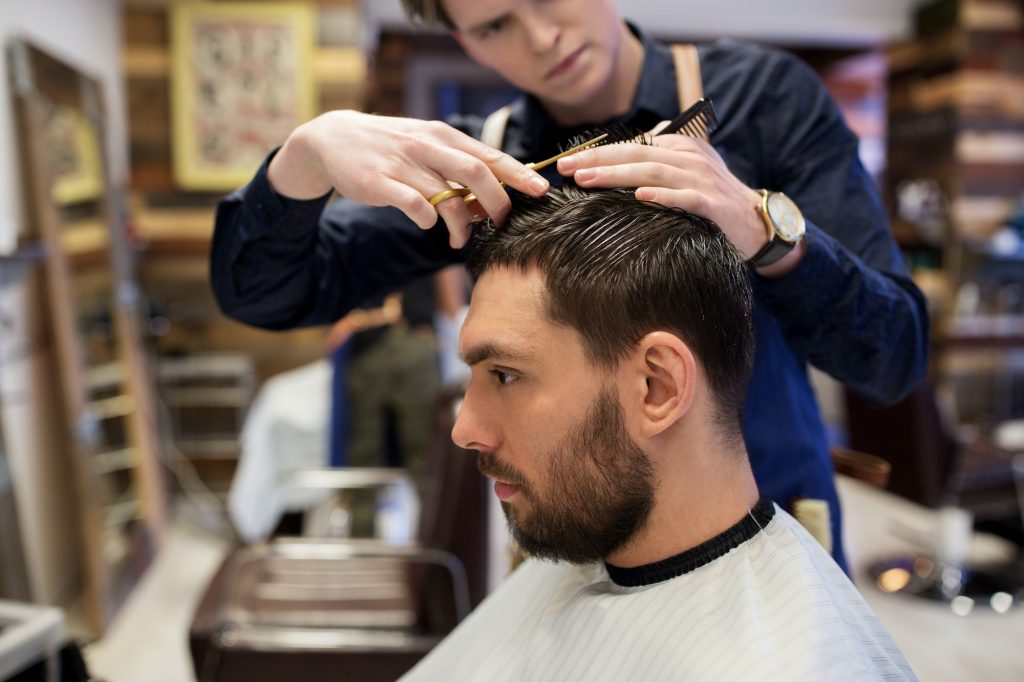 man and barber cutting hair at barbershop