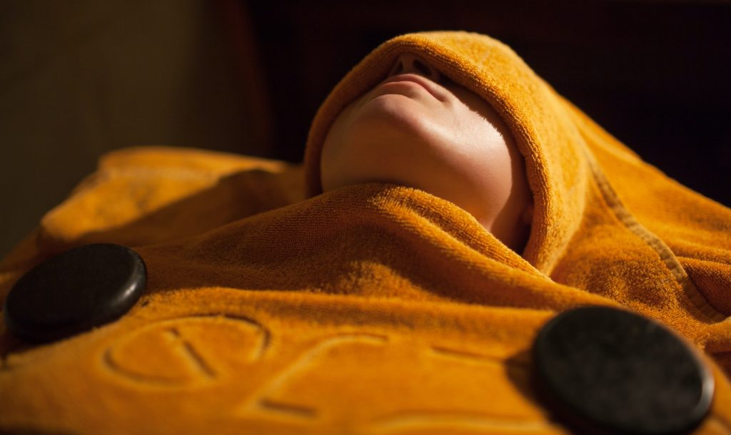 Woman getting hot towel treatment at beauty spa